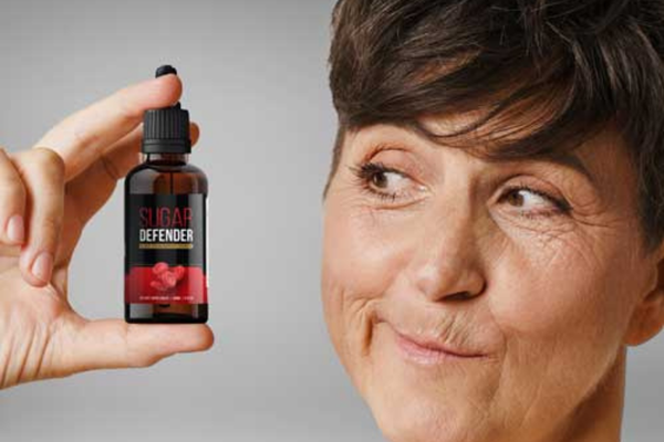 A smiling woman holding a bottle of Sugar Defender supplement close to her face, looking at it with a confident expression.